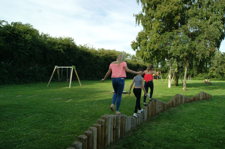 Girls walking along a raised wooden platform in a park.